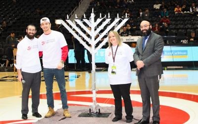 Rabbi Yale New, Ben Massey, Emily Hanover and Rabbi Isser New bask in the light of the menorah before tipoff of the Hawks’ home game against the Heat.