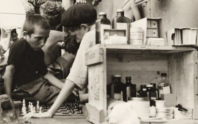 Children playing chess on the refugees’ deck of the Henry Gibbins next to an outdoor medical station and pharmacy, 1944. (photo credit: Ruth Gruber)