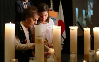Holocaust survivor Janine Storch lights a memorial candle with the help of Emma Novitz.