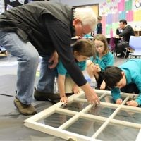 Photo courtesy of the Davis Academy
First-graders get guidance from an experienced hand in painting menschlichkeit values on a window.