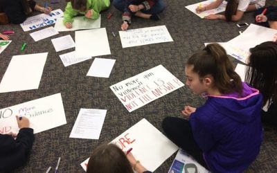Middle-schoolers at Temple Emanu-El work on posters March 18 for the March for Our Lives on March 24. (Photo by Bob Bahr)