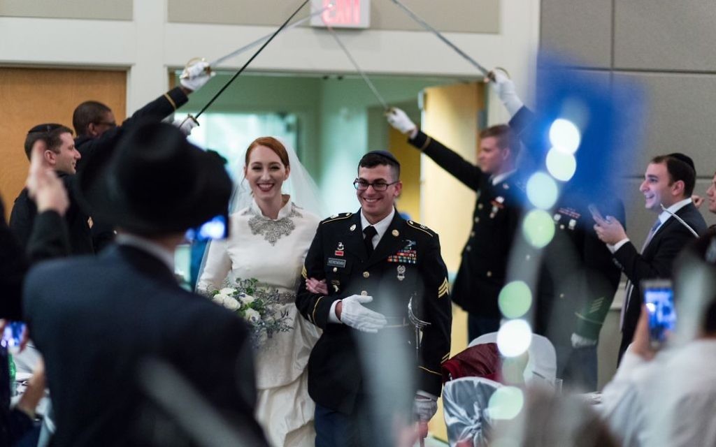 Keeping with military tradition, Ashley and Natan walk through an arch of sabers on their wedding day in Congregation Beth Jacob’s Heritage Hall.