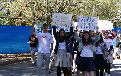 The walkout circles Atlanta Jewish Academy as students hold up protest signs.
