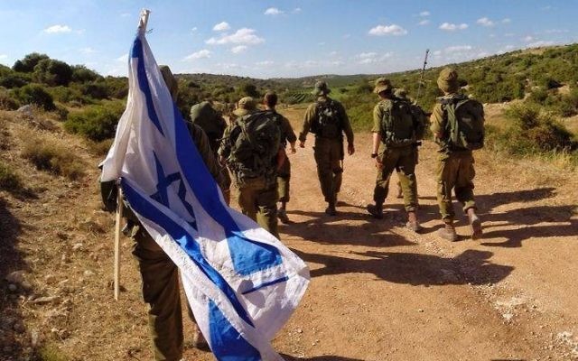 IDF soldiers march with the Israeli flag.