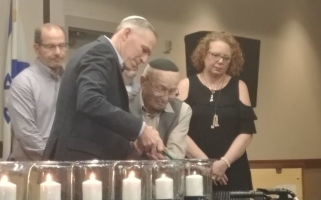 Ken Winkler helps Holocaust survivor Bernie Gross light the last candle as Margie Gelernter looks on. (Photo by Sarah Moosazadeh)