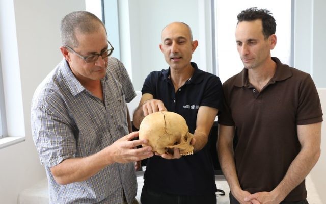 (From left) Boaz Zissu, Yossi Nagar and Haim Cohen examine the skull of what is believed to be a victim of blood vengeance. (Israel Antiquities Authority photo)