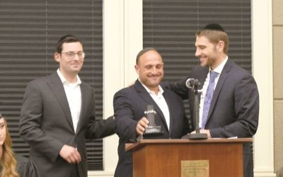 Executive Director Rabbi Yitzchok Tendler presents a tribute to Shalom Teller  for his service with presenter Rabbi Doron Silverman (right)