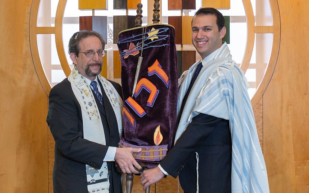 Emeritus Rabbi Harvey Winokur (left) passes a Czech Torah scroll that survived the Holocaust to Rabbi Jason Holtz.
