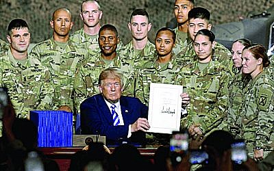 US President Donald Trump holds the John S. McCain National Defense Authorization Act for FY 2019.