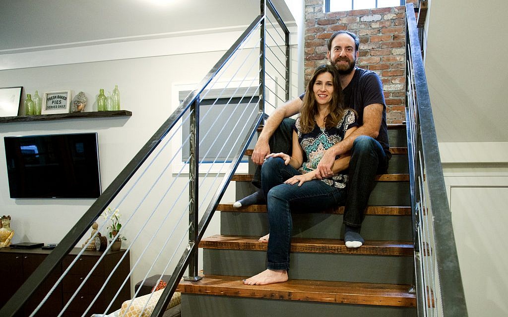 Photos by Laurie Sermos // Lauren and Mark Chekanow relax on the repurposed wood stairs in front of the brick wall that was restored from the original fireplace.