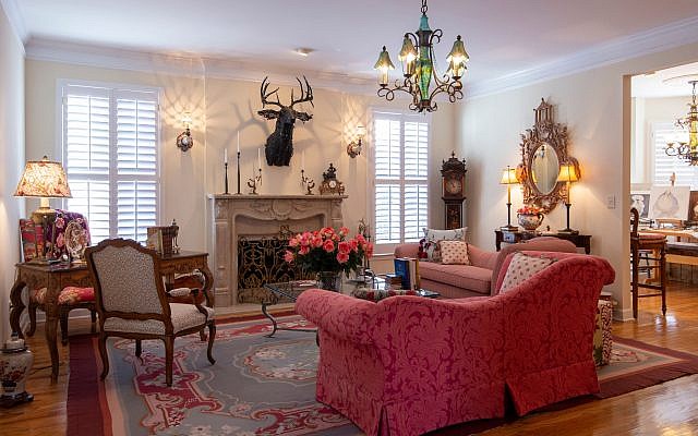 Great Room: The deer head made of canvas strips presides over a custom-limestone mantel. The sconces are porcelain hands holding candles with MacKenzie-Childs cut glass lamp shades. The andirons are from a store on Lake Burton. The cranberry rug is Obsidian.