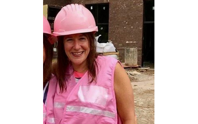 Amy Fingerhut in a pink hardhat on a construction site.