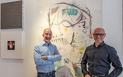 Photos by Dark Rush // From left, Philip and Robert flank original mixed media drawing by Canadian Doug Stone.  The silver square is “Confetti Painting” by Jim Oliveira,  poured resin on canvas. “Self Portait” on left is by Brooklyn artist Jim Confalone.