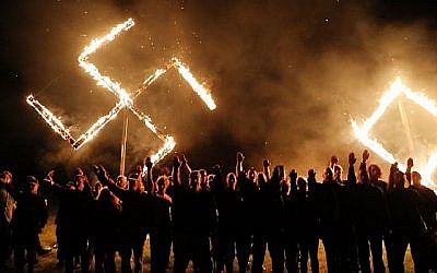 Spencer Platt/Getty Images/AFP // Members of the National Socialist Movement, one of the largest neo-Nazi groups in the U.S., hold a swastika burning after a rally on April 21, 2018, in Draketown, Ga.