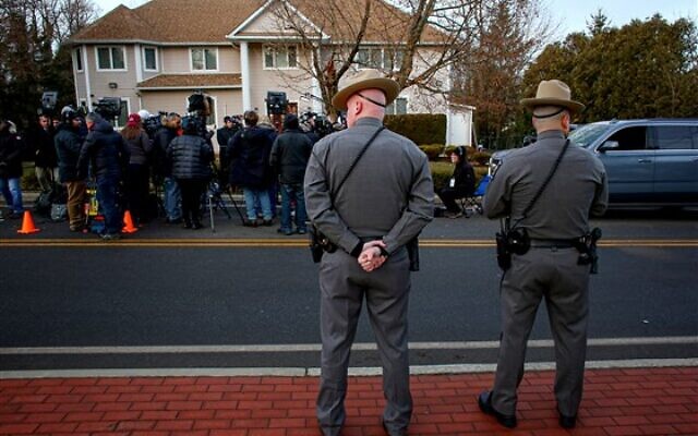 Police stand guard on Sunday as news media gather outside the home of a rabbi where five people were injured in a machete attack during a Hanukkah gathering in Monsey, New York.Kena Betancur / AFP - Getty Images
