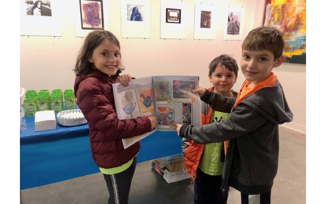 Davis Academy fifth grader Leora Sokol and her brothers pose with the AJT, pointing at her submission.