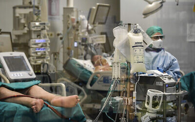 In this photograph taken from behind a window, doctors work on Covid-19 patients in the intensive care unit of San Matteo Hospital, in Pavia, northern Italy, Thursday, March 26, 2020. The San Matteo hospital is where Patient 1, a 38-year-old Unilever worker named Mattia, was kept since he tested positive for Covid-19 on Feb. 21 and opened Italy’s health care crisis. The new coronavirus causes mild or moderate symptoms for most people, but for some, especially older adults and people with existing health problems, it can cause more severe illness or death. (Claudio Furlan/LaPresse via AP)