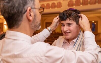Noah Lipis puts on tefillin for the first time with his cantor.