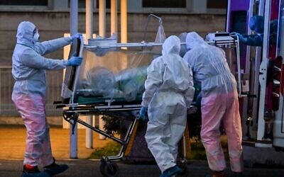 Medical workers in overalls bring a patient under intensive care into the newly built Columbus Covid 2 temporary hospital to fight the new coronavirus infection, at the Gemelli hospital in Rome, on March 16, 2020. (ANDREAS SOLARO/AFP)