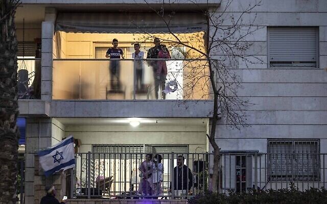 Israeli families stand on their balconies and applaud medical teams fighting the coronavirus outbreak in the town of Ashkelon, March 19, 2020. (AP Photo/Tsafrir Abayov)
