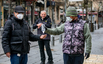 A merchant selling alcogel hand sanitizer to passersby in central Jerusalem on March 18, 2020. (Olivier Fitoussi/FLASH90)
