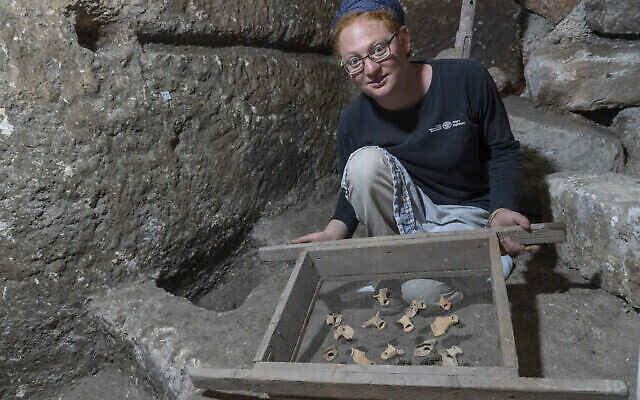 Excavation co-director Tehila Saldiel showing some of the artifacts from the excavations under Beit Straus in Jerusalem’s Old City, near the Western Wall, May 2020. (Shai HaLevi/Israel Antiquities Authority)