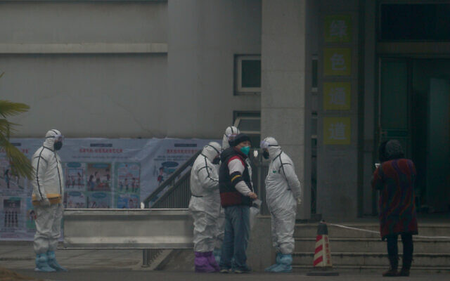 Staff in biohazard suits hold a metal stretcher by the in-patient department of Wuhan Medical Treatment Center, where some infected with a novel coronavirus are being treated, in Wuhan, China, Tuesday, Jan. 21, 2020. Heightened precautions were being taken in China and elsewhere Tuesday as governments strove to control the outbreak of the coronavirus, which threatens to grow during the Lunar New Year travel rush. (AP Photo/Dake Kang)