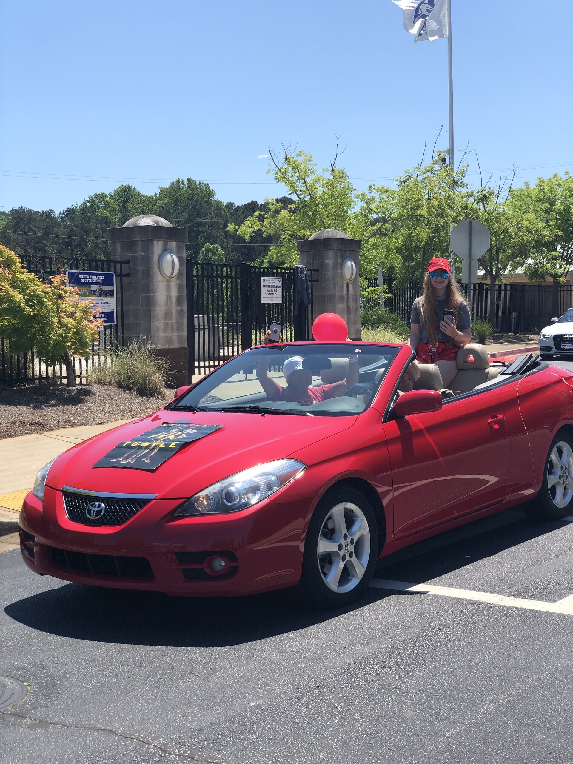 Brooke Orenstein pops out of her red convertible as part of the Weber senior commitment day parade.
