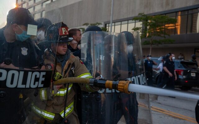 Atlanta police protect a fireman as he extinguishes a police cruiser lit aflame by protesters in the clash outside CNN Center May 29.