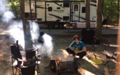 Doran Levin, 15, tends the campfire in front of the rented RV.