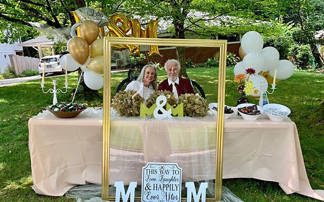 Mira Bergen and Michael Mann pose inside an empty frame, among the curbside engagement party decorations.