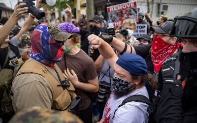 A counter-protester throws his fist in the air as militia members face off against counter-protesters in downtown Stone Mountain. // Nathan Posner of AJT