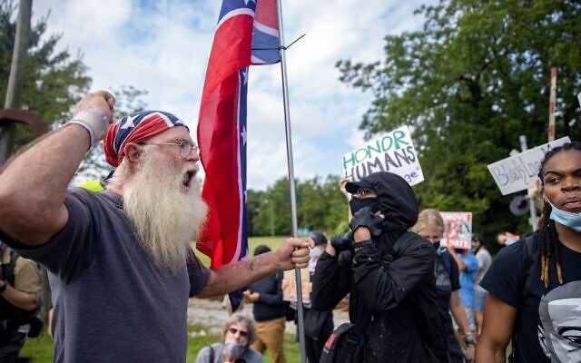 A man with a Confederate flag faces off against counter-protesters. // Nathan Posner of AJT