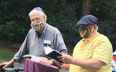 Rabbi Michael Kramer and Allen Lipis test unamplified sound while praying from an outdoor podium.