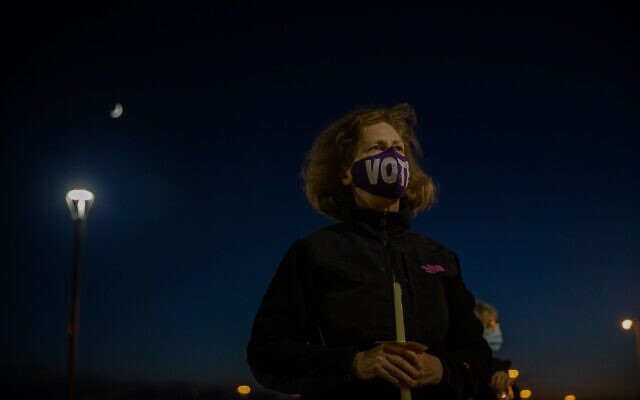A woman holds a candle in memory of the late Justice Ginsburg at a candlelight vigil in her memory. // Nathan Posner for the AJT.