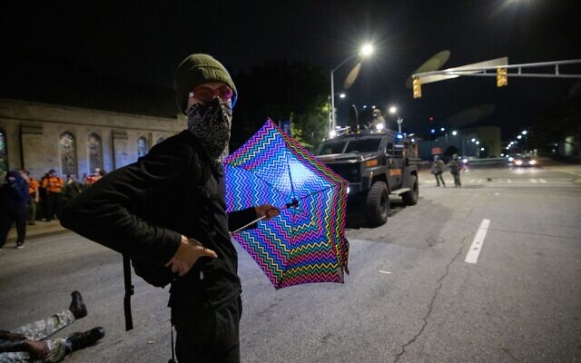 A protester holds an umbrella as state troopers, in a BearCat vehicle begin to push forward against protesters. // Nathan Posner for the AJT.
