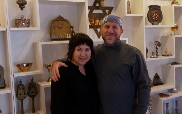 Elihu Siegman and Nancy Sokolove stand in front of a section of their Judaica collection wall.