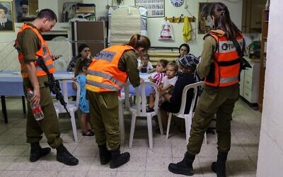 Israeli soldiers from Home Front Command visit families inside a bomb shelter in the southern Israeli city of Ashkelon, on May 18, 2021. (Menahem KAHANA / AFP)