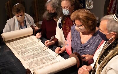 Judi Kern holds the Torah scroll open as Bobby Horowitz looks on. Shelly Pirkle, Genie Nickelsberg and Denise Whitlock read the Hebrew.
