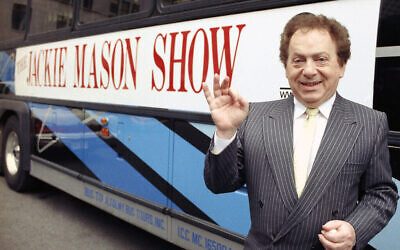 Actor/comedian Jackie Mason in 1992 standing beside a bus displaying a sign advertising his TV show, 1992. (AP Photo)