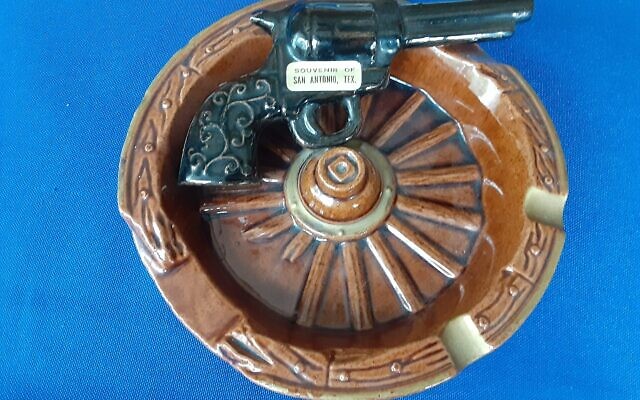 Iconic guns are portrayed on ashtrays, including a famous Colt pistol, patented in 1836.