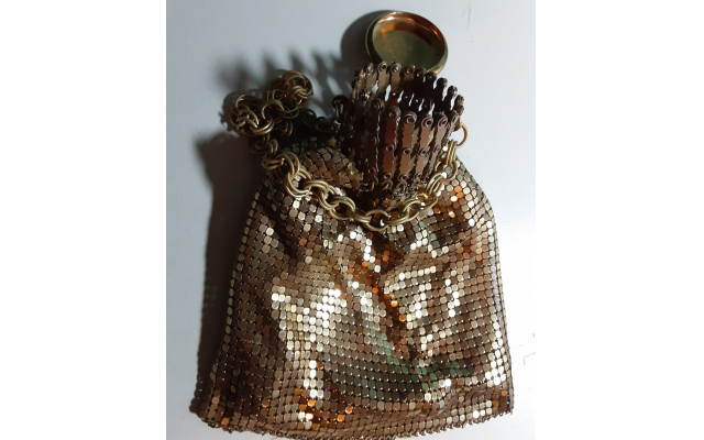 Gold metal mesh bag with accordion opening and removable cap.