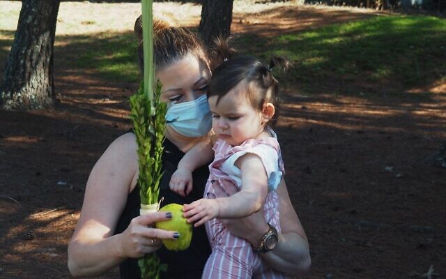 Allison Budnick and daughter Mila shake the lulav and etrog in honor of the Sukkot holiday.