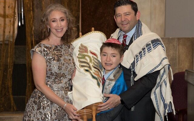 Sam holds the TKE Torah with his parents by his side.