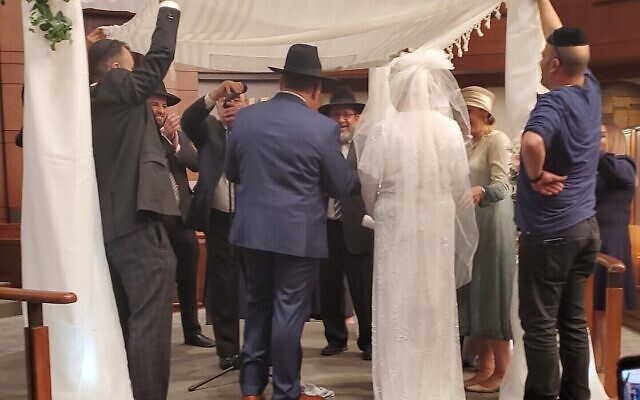 Groom’s tallit is held above the wedding couple, under a chuppah designed and built by Rachel Lovett.