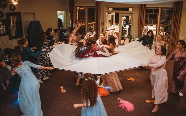 Bride and her friends dance, as friends circle wedding parachute.