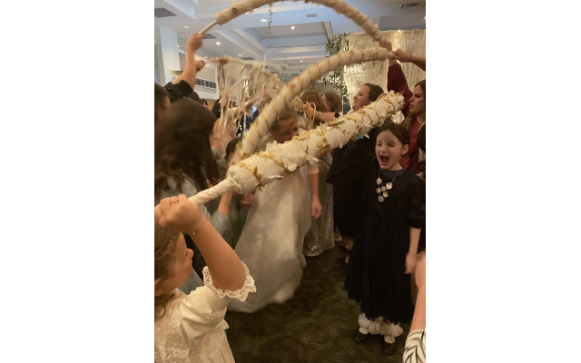 Bride and groom enter wedding reception through decorated hand-held arches.