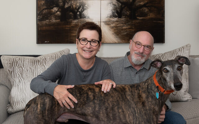 Photo by Howard Mendel // Patti and Jerry with their rescue greyhound Petey. Background painting by John Folsom, “Magnolia Gardens Pathway,” 2004.