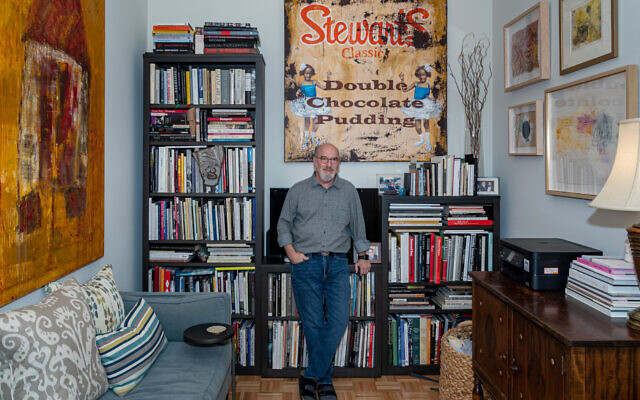 Photo by Howard Mendel // A pensive Jerry Siegel relaxes in his study, with (left) his own “House/Home,” (oil stick on canvas) and “Stewart’s Classic, Double Chocolate Pudding” by Cedric Smith.