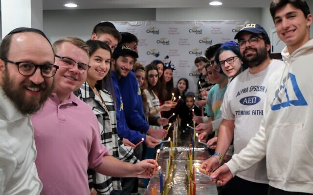 Students light menorahs at Kennesaw State Chabad Chanukah party.